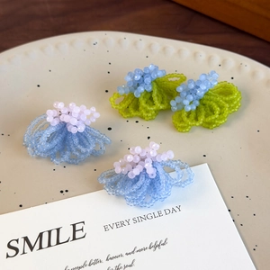 Handcrafted matte crystal beaded earrings in floral shape on a cream ceramic plate
