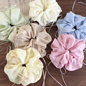 Lot de six chouchous en organza avec nœud en couleurs pastel sur fond en bois rustique