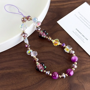Detailed close-up of handmade beaded phone strap with purple bears on wood background