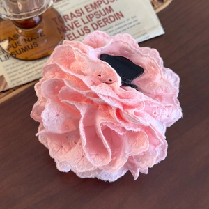 Detail of pink lace rose hair claw clip with floral embroidery on retro wood background