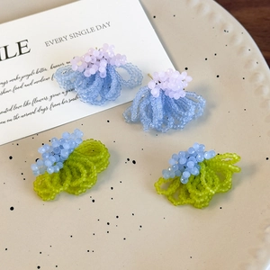 Close-up of handmade frosted crystal beaded flower stud earrings in purple and blue