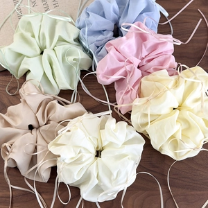 Détail de six chouchous en satin pastel avec rubans sur fond en bois de noyer foncé
