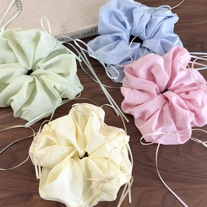 Détail de quatre chouchous en organza aux couleurs pastel sur une surface en bois