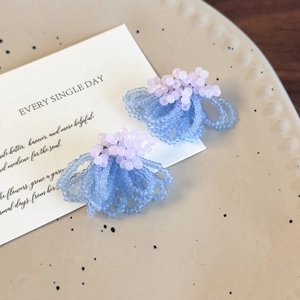 Macro detail of blue crystal beaded stud earrings on elegant ceramic tray