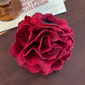 Detailed view of burgundy lace flower hair claw with intricate embroidery on wood surface