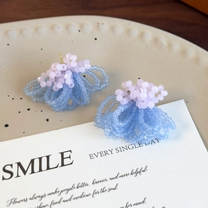 Detail shot of matte blue and pink crystal beaded flower cluster earrings on ceramic plate