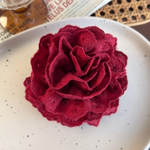 Detailed close-up of a red embroidered flower hair claw with intricate lace petals
