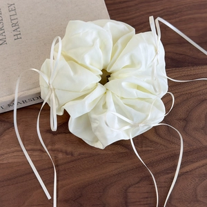 Détail d'un chouchou en organza crème avec de petits nœuds en ruban sur un fond élégant