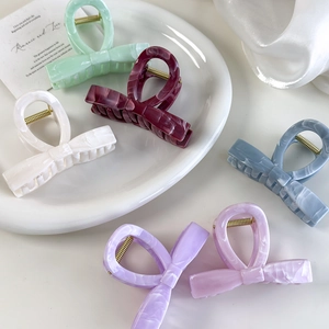 Elegant jelly-colored bow hair claws in Morandi tones displayed on a ceramic plate