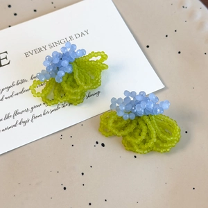 Detail of handmade beaded earrings with light blue crystals and green frosted beads
