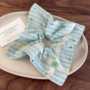 Détail d'un chouchou géant à rayures vertes avec bordure en dentelle et petit bouton