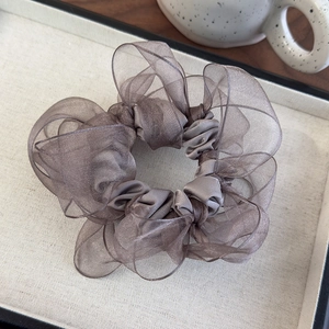 Detail of grey organza oversized scrunchie with layered pleated texture and metallic sheen