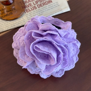 Detailed close-up of purple lace rose hair claw with intricate embroidery on wood surface