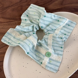 Vue détaillée du chouchou rayé vert avec bordure en dentelle et bouton sur un plateau en céramique