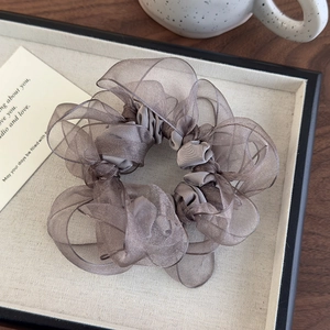 Detail of grey organza scrunchie showing pleated texture and voluminous translucent fabric