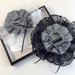 Detail of plaid scrunchies with lace trim and small black ribbon bows in a tray