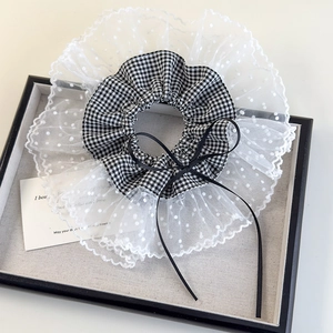 Macro view of lace ruffled scrunchie with black gingham fabric and silk ribbon bow