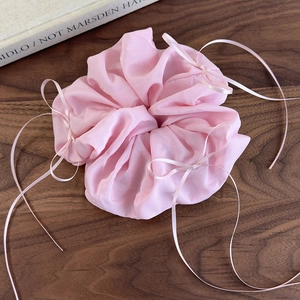 Détails du chouchou rose géant en organza avec rubans sur une table en bois sombre