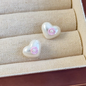 Detailaufnahme herzförmiger Perlenohrstecker mit rosa Blumeneinlage auf Samtkissen