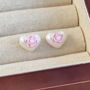 Detaillierte Makroansicht von herzförmigen Perlenohrringen mit kleiner rosa Blume und Harz