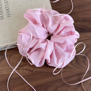 Détail d'un chouchou en organza rose avec ruban nœud sur fond en bois sombre élégant