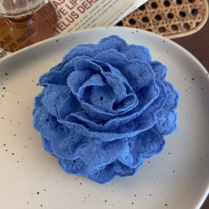 Detailed embroidery of blue lace rose hair claw clip on a stylish ceramic plate