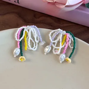 Détail de boucles d'oreilles faites main avec perles colorées et breloques fleurs