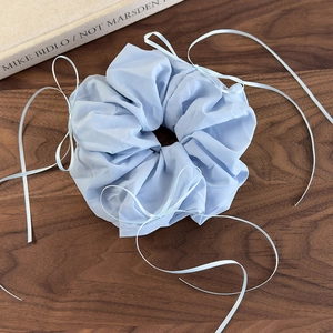 Détail d'un chouchou en organza bleu clair avec rubans sur un fond en bois rustique