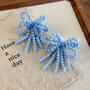 Détail de nœuds de chaussures en perles bleu clair avec franges sur fond papier beige