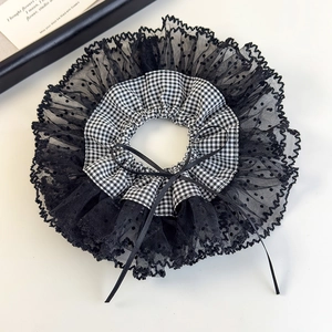 Detailed macro of a French lace scrunchie with gingham patterns and a black ribbon bow