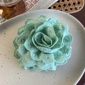 Detailed macro view of mint green lace embroidery flower hair claw with floral texture