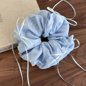 Détail d'un chouchou en organza bleu clair avec rubans sur surface en bois