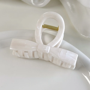 Close-up of elegant cream-white marble acetate hair claw clip with golden metal spring