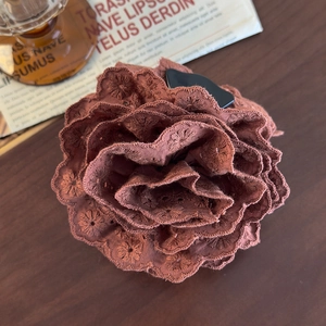 Close-up of brown lace floral hair claw with detailed embroidery on a dark wood background