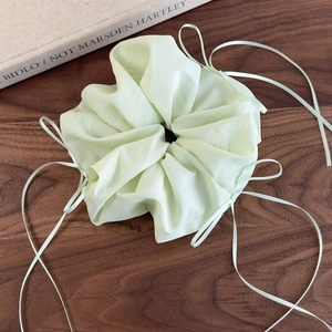 Détail de la texture d'un chouchou en organza vert menthe avec longs rubans en satin