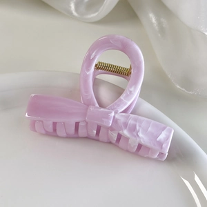 Macro shot of pink bow hair claw clip with marble texture and gold metal spring details