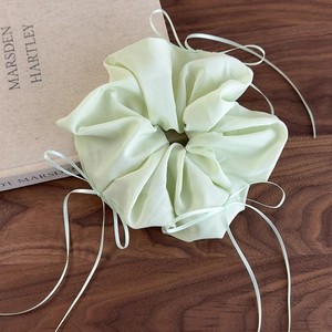 Gros plan d'un chouchou en organza vert menthe avec rubans sur une table bois