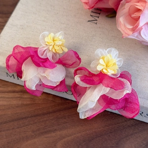 Detail of pink organza layered flower earrings on a book with soft floral background