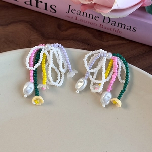 Gros plan de boucles d'oreilles nœuds faites main en perles colorées et fleurs jaunes