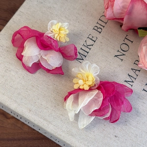 Detailed macro view of 3D layered pink organza flower hair accessories on linen