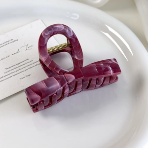 Close-up of a burgundy marble acetate bow hair claw clip with strong metal spring