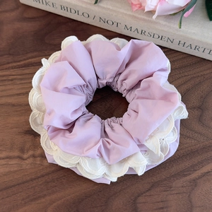 Dettaglio di un elastico per capelli in tessuto rosa con pizzo su tavolo di legno