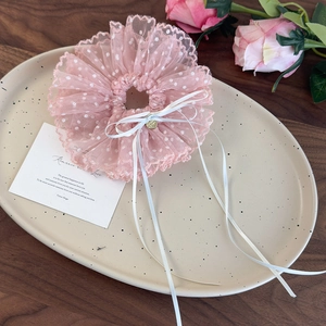 Dettaglio di elastico per capelli in pizzo rosa a pois con fiocco e cuore dorato