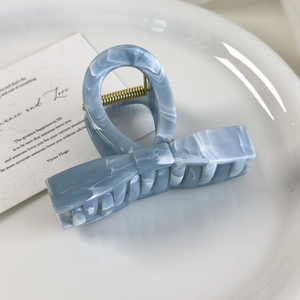 Detailed macro view of light blue marble acetate hair claw with golden spring mechanism