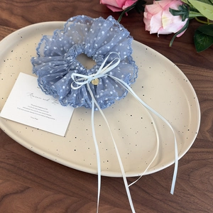 Dettaglio di elastico per capelli in pizzo blu a pois con fiocco e ciondolo a cuore