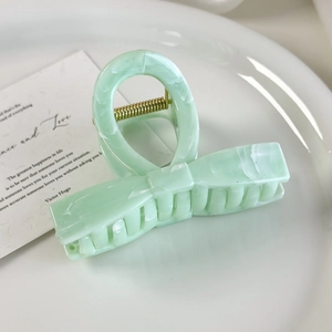 Detail of light green marble texture hair claw clip with bow design and gold spring
