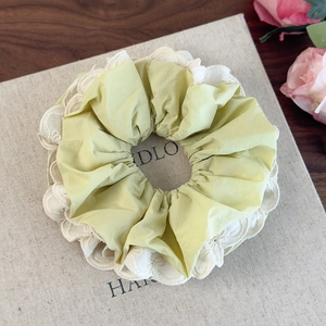Dettaglio ravvicinato di un elastico per capelli giallo con pizzo bianco elegante