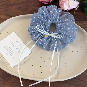 Dettaglio dell'elastico in pizzo azzurro a pois bianchi con ciondolo a cuore dorato