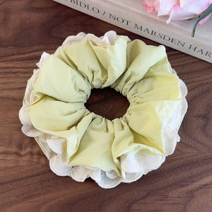 Dettaglio dell'elastico in tessuto giallo con delicato bordo in pizzo bianco ricamato