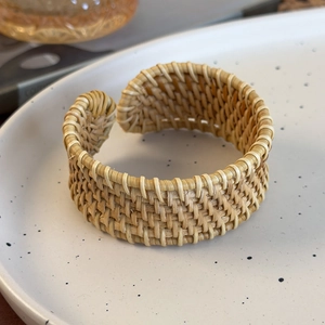 Gros plan d'un bracelet en rotin tressé à la main avec texture naturelle sur un plateau blanc